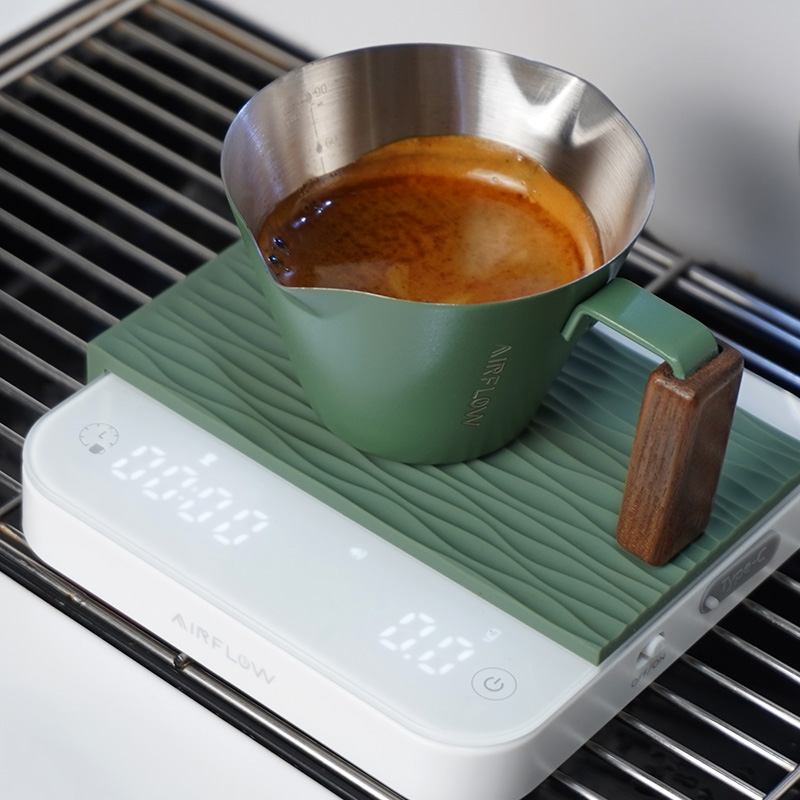 Green Airflow espresso shot cup with walnut handle on an Airflow scale over a drip tray.